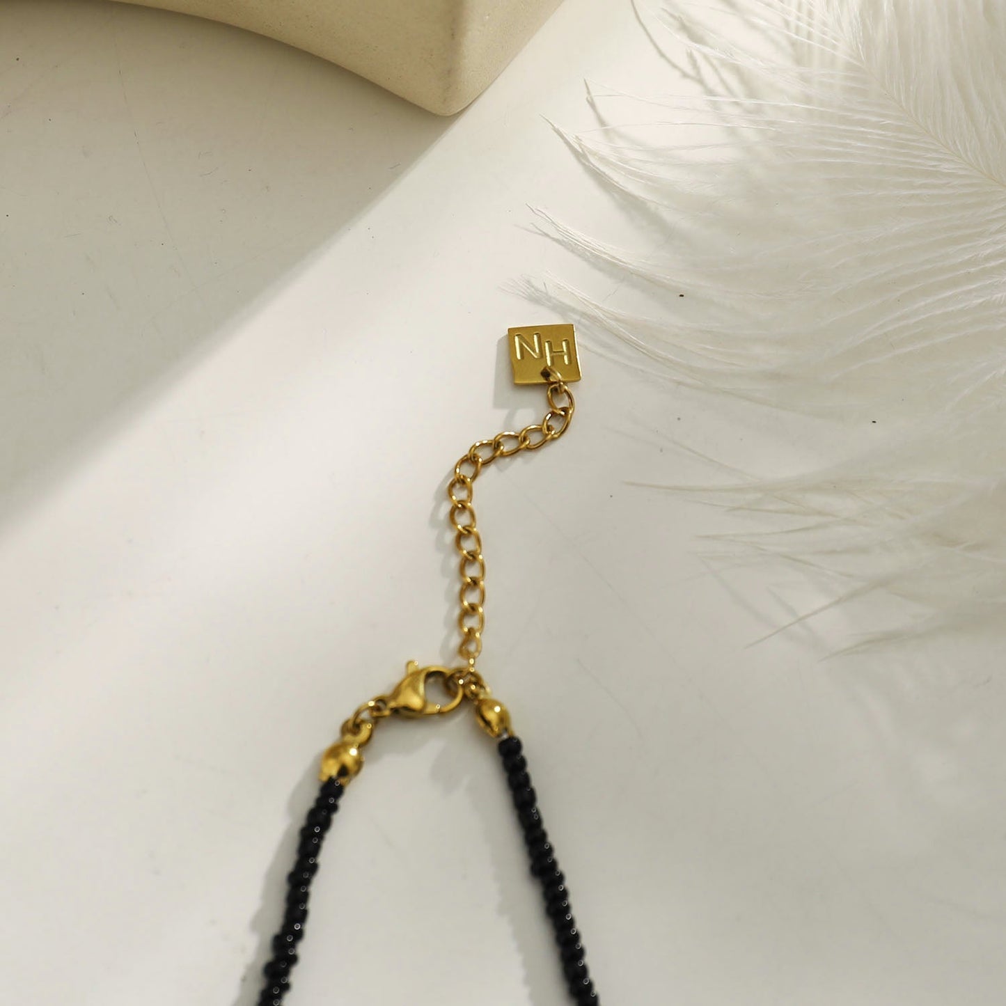 Collier chaîne RITA à perles noires et dorées avec pendentif dent gravée en or