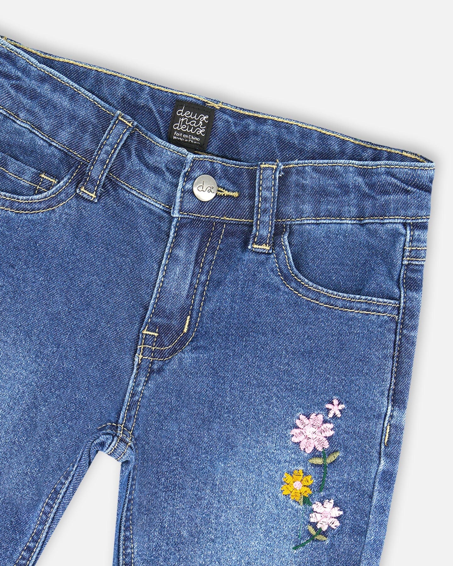 Jean bleu en denim avec ourlets effilochés et broderies florales