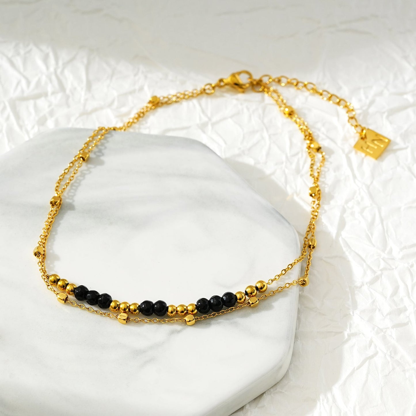 HILDA LG : Bracelet de cheville perles carrées et perles rondes deux-en-un noir et or.