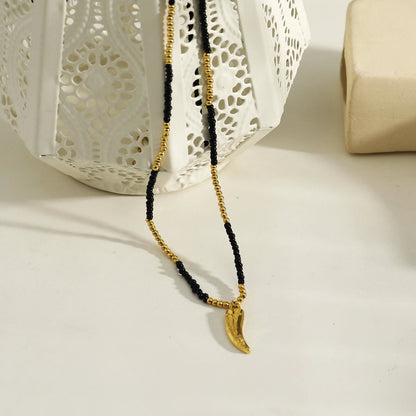 Collier chaîne RITA à perles noires et dorées avec pendentif dent gravée en or