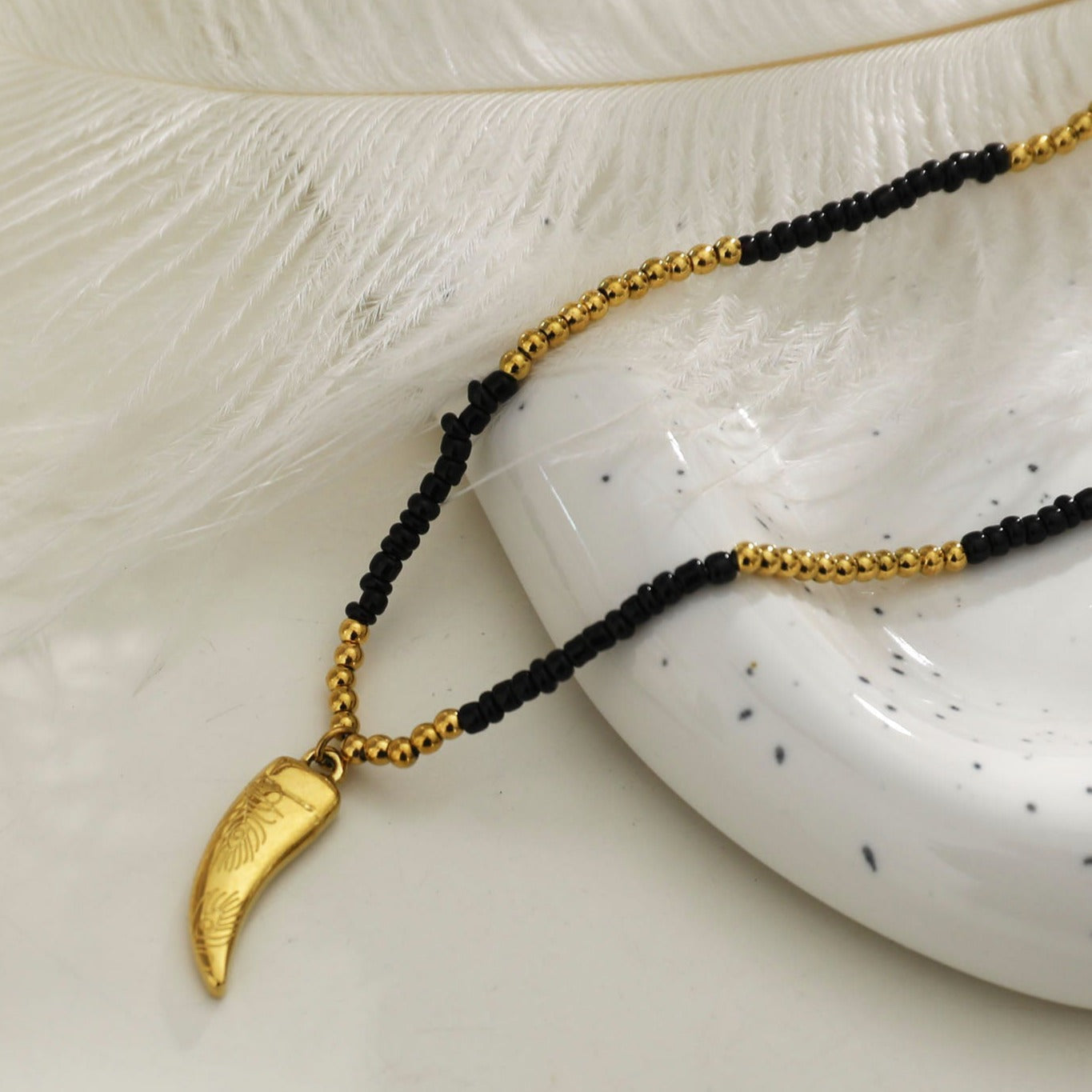 Collier chaîne RITA à perles noires et dorées avec pendentif dent gravée en or