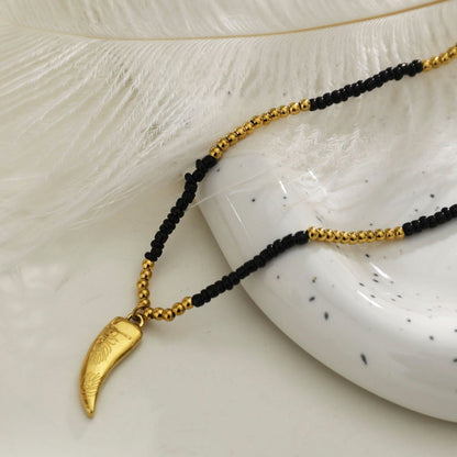 Collier chaîne RITA à perles noires et dorées avec pendentif dent gravée en or