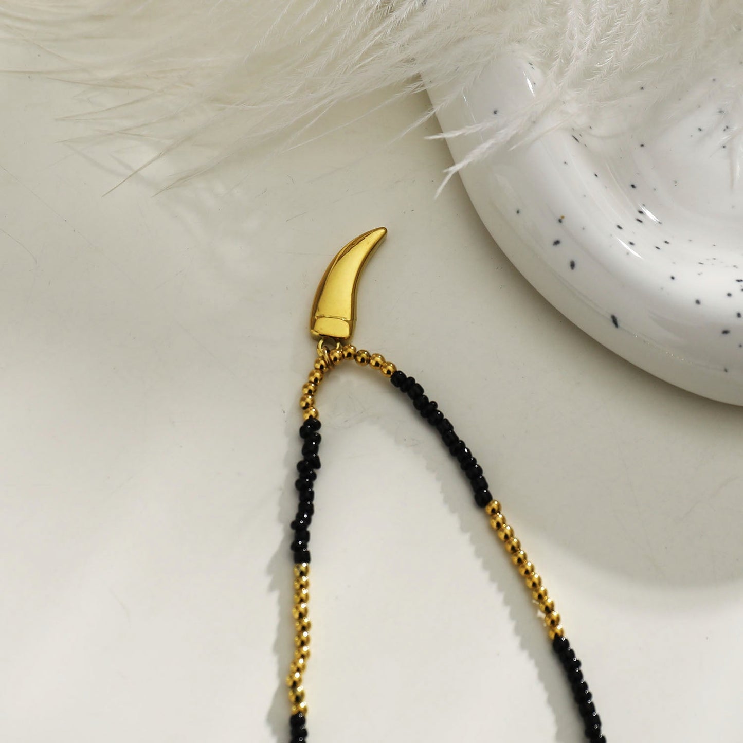 Collier chaîne RITA à perles noires et dorées avec pendentif dent gravée en or