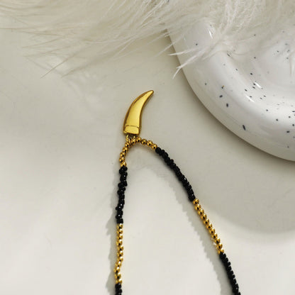 Collier chaîne RITA à perles noires et dorées avec pendentif dent gravée en or
