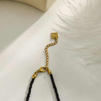 Collier chaîne RITA à perles noires et dorées avec pendentif dent gravée en or