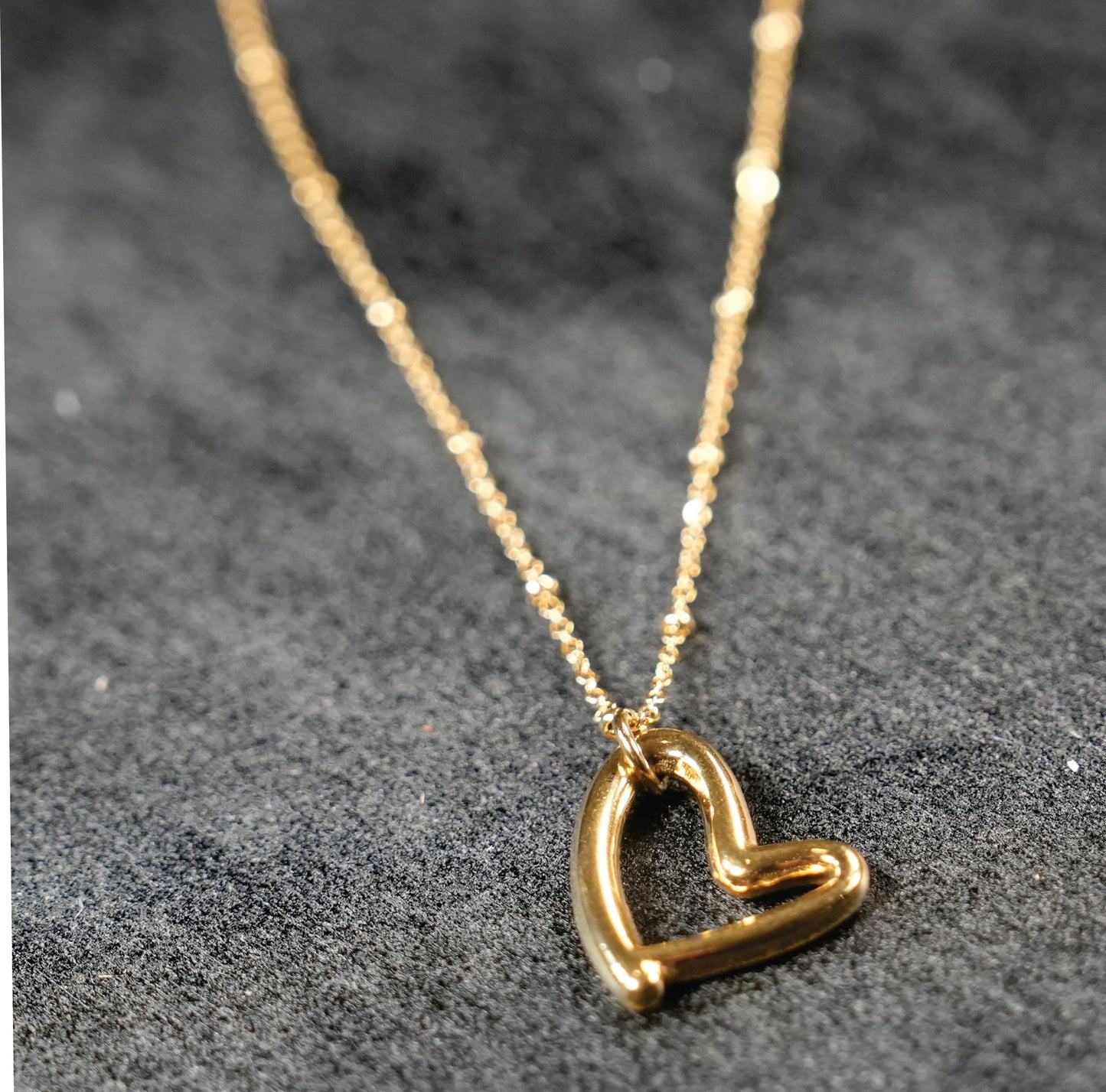 SMITTEN Gold : Une fine chaîne perlée retenant un pendentif en forme de cœur abstrait