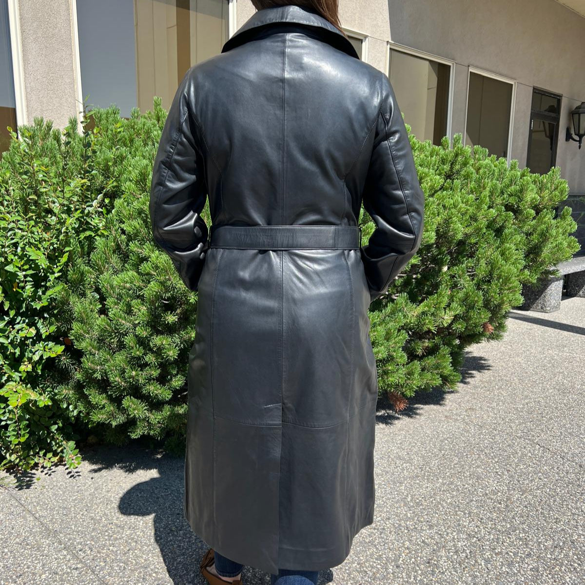 Trench-coat classique en cuir pour femme. Double boutonnage avec ceinture ajustable.
