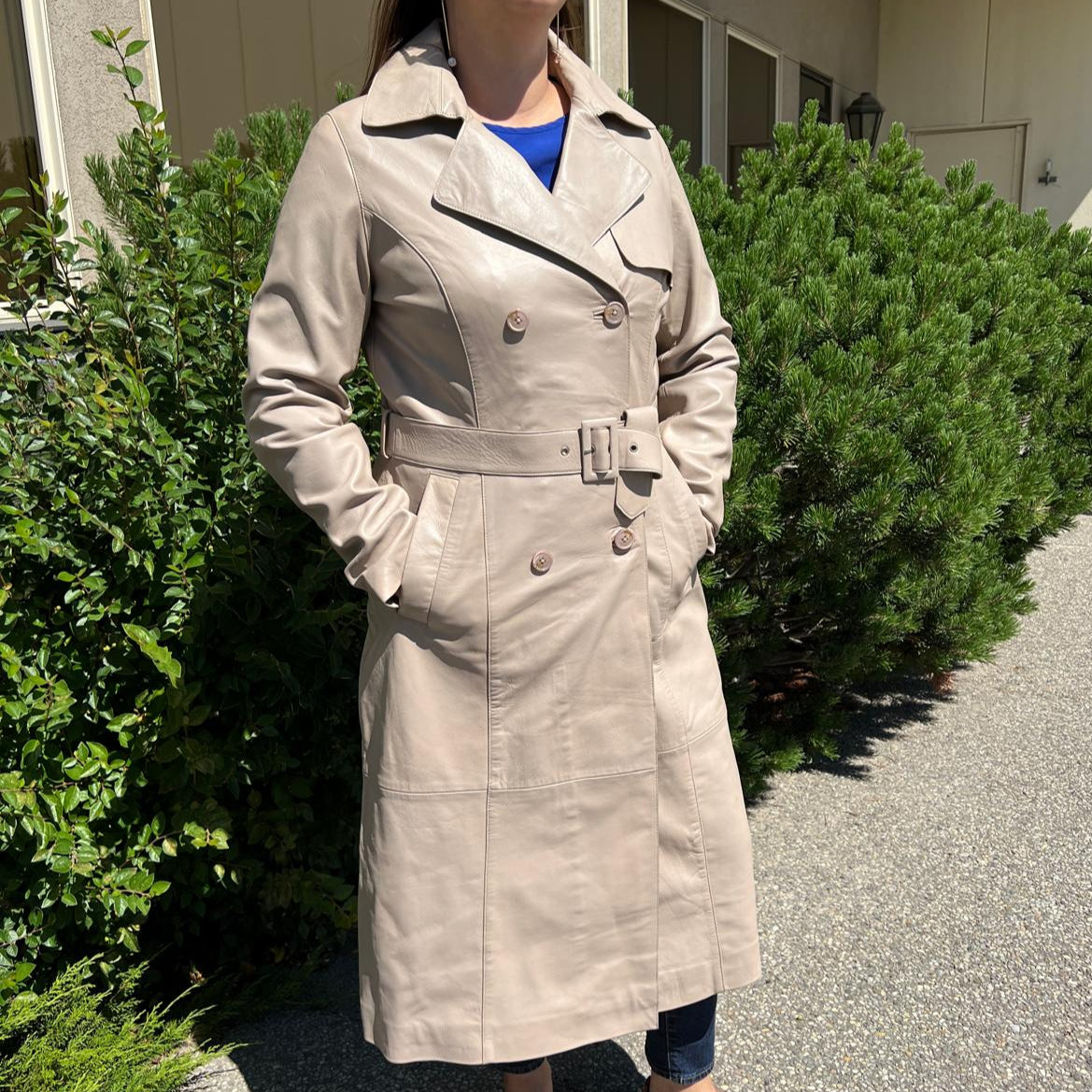 Trench-coat classique en cuir pour femme. Double boutonnage avec ceinture ajustable.