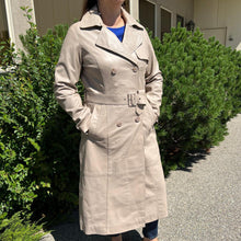 Trench-coat classique en cuir pour femme. Double boutonnage avec ceinture ajustable.