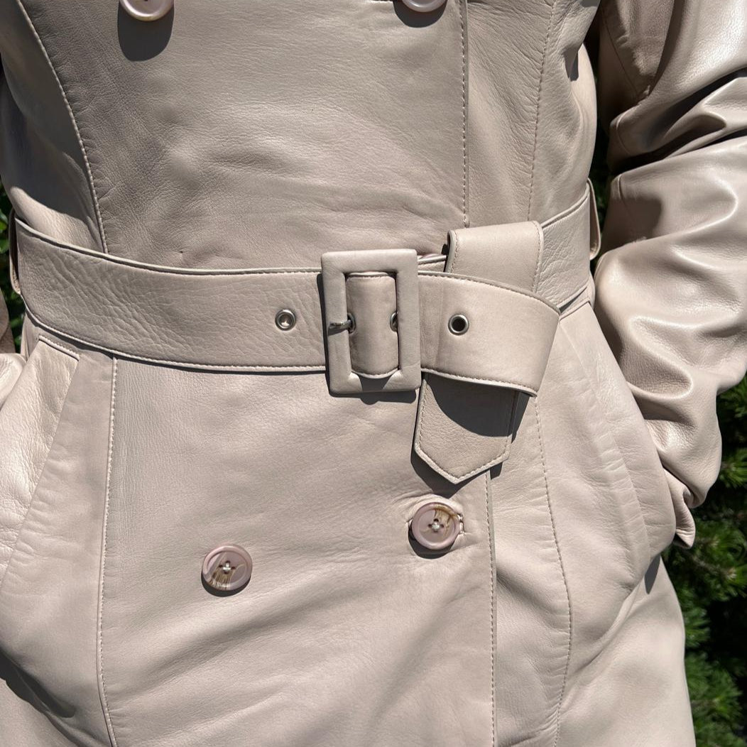 Trench-coat classique en cuir pour femme. Double boutonnage avec ceinture ajustable.