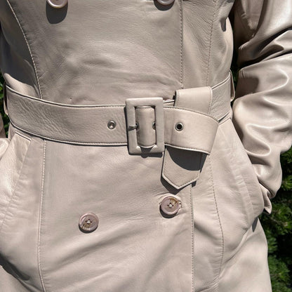 Trench-coat classique en cuir pour femme. Double boutonnage avec ceinture ajustable.